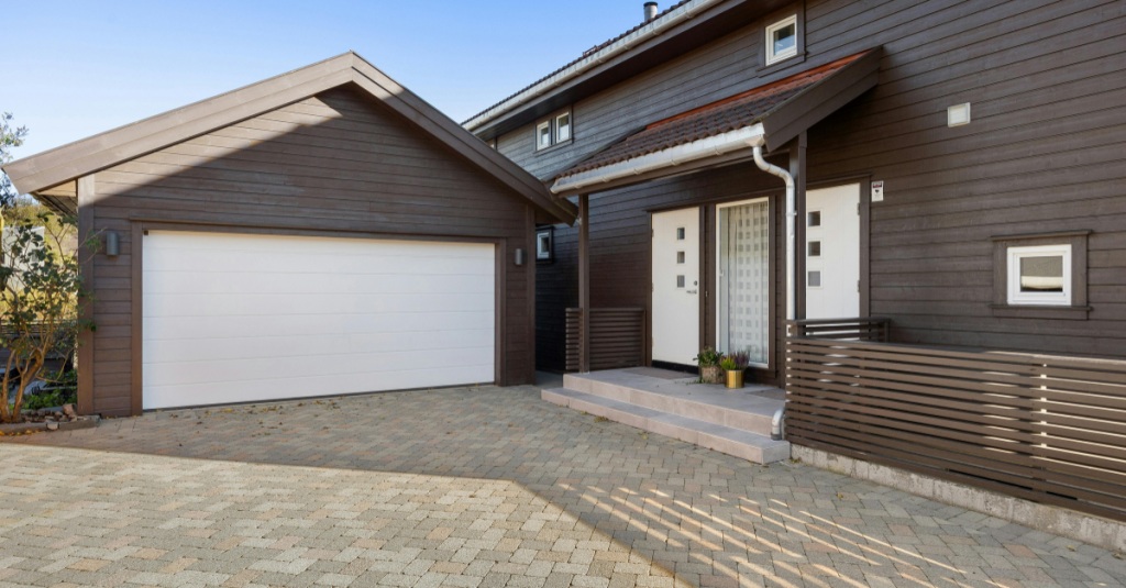 Attached garage with white doors connected to a dark brick home