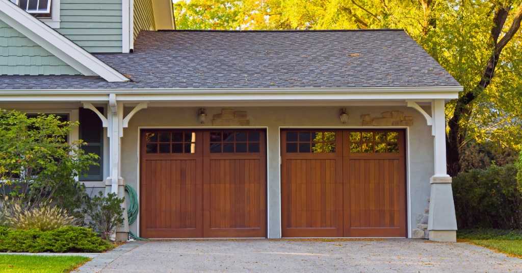 Detached garage with wood doors and stone columns under a gabled roof