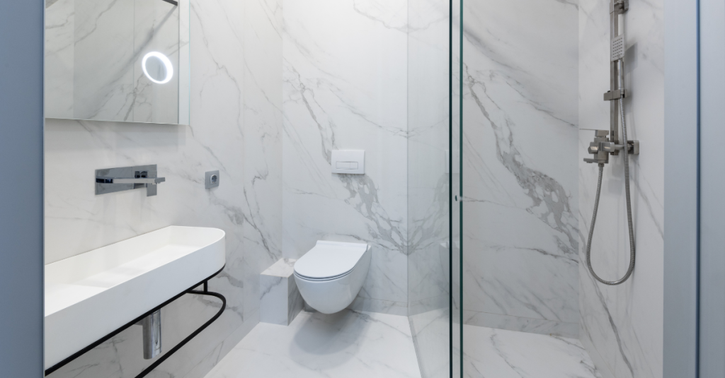 White zero-threshold shower with wall-mounted toilet and grab bars.