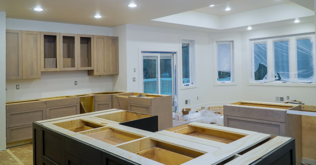 Light wood wall cabinets and a dark-framed island under construction.