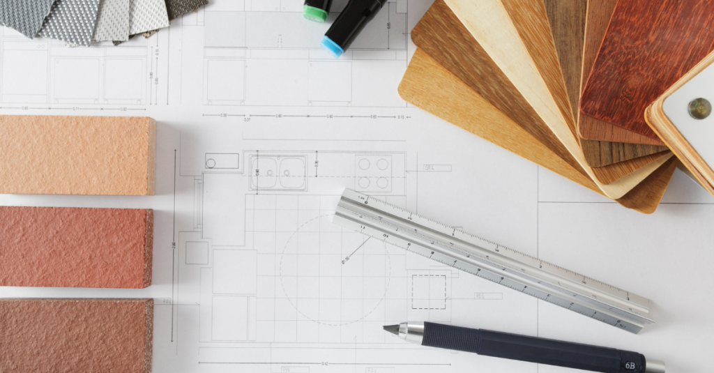 Blueprints with wood veneer samples, tile samples, a ruler, and drafting tools.